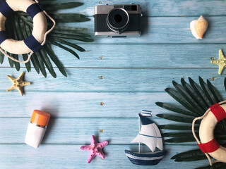 Summer season theme with Camera and boat and suntan lotion and starfish with shell on wooden blue background. Planing for summer season. Tourist travel on holiday and happy. Summer and Holiday concept