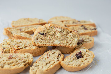 Close up Italian biscotti cookies on baking paper. Fresh baked cookies with nuts and dried cranberries with selective focus. Copy space. Classic recipe