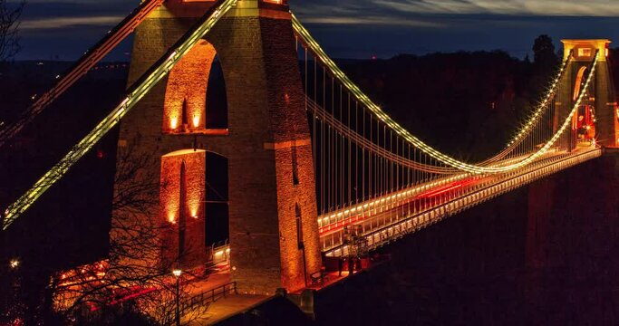 Long exposure night timelapse of Clifton Suspension Bridge tower with the city lights of Bristol, UK in the background