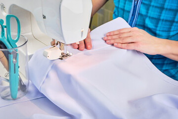Woman's hands sew on a sewing machine close up