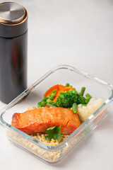 Salmon fillets with bulgur and vegetables in the container. Diet nutrition.