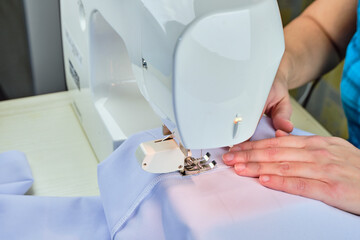 Woman's hands sew on a sewing machine close up