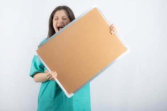 Screaming young medical worker holding a board with hands
