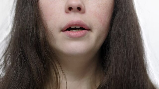 Drowsiness and fatigue. A young, sleepy woman yawns. Close-up view. White background. Soft focus.