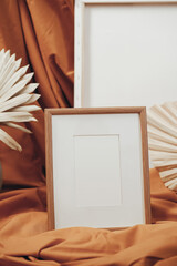 White blank wooden frames in an artistic interior with a mustard-colored cloth, near dried flowers in a clay vase