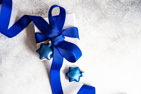 Wrapped gift box tied with a blue ribbon and Christmas baubles