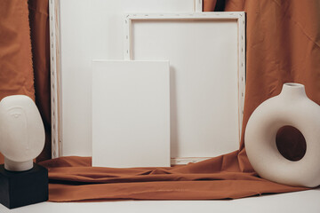 White blank canvases in an artistic interior with a mustard-colored cloth, near dried flowers in a clay vase