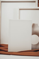 White blank canvases in an artistic interior with a mustard-colored cloth, near dried flowers in a clay vase