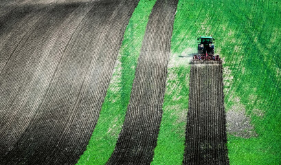 Sunshine view of big tractor plowing the ground of green field on the slope