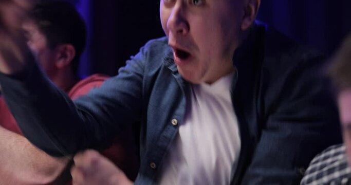 Close up of Worried Caucasian Male Football Fan Sitting With Friends at TV Screen in Room and Watching Match. Cheerful Man Celebrating Football Win. Scoring Goal or Winning Game Concept