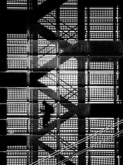 Czarno-białe graficzne pionowe ujęcie mężczyzny na metalowej klatce schodowej