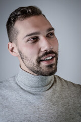 Obraz premium Portrait of a young brown-haired man with a short beard and a gray turtleneck sweater 