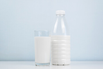 Morning healthy breakfast concept. Glass of milk, bottle standing on a white table. Minimalistic photo.