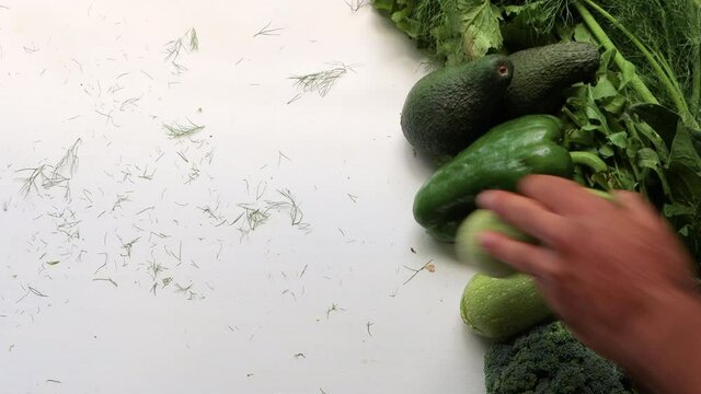 Male hand takes zucchini on healthy food clean eating selection: fruit, vegetable, avocado, spinach superfood, leaf vegetable