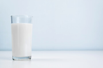 Glass of milk standing on white table, indoors. Minimalistic photo, copy space. Healthy food, diet concept