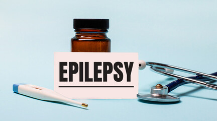 On a blue background - a bottle for pills, a stethoscope, an electronic thermometer and a card with...
