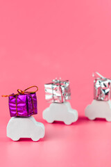 Gift delivery concept. Toy car delivers gift box on pink background. February 14 postcard, Valentine's Day, Christmas, New year, 
 March 8, international women's day. Minimalism style.