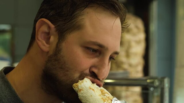 a young man eats shawarma in an institution for a quick lunch,4k