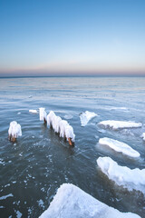 Ice breakwaters, covered with snow, stand in the winter sea. sea winter landscape background.
