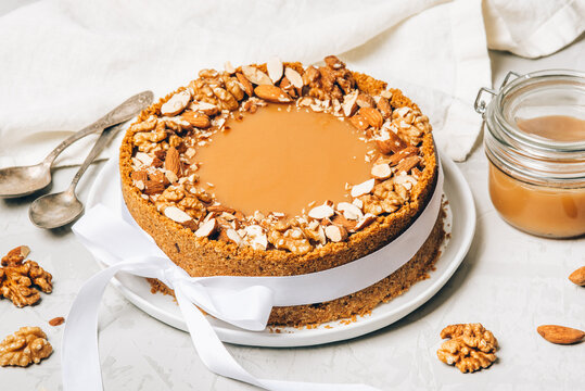 Cheesecake with salted caramel and nuts on a gray background.