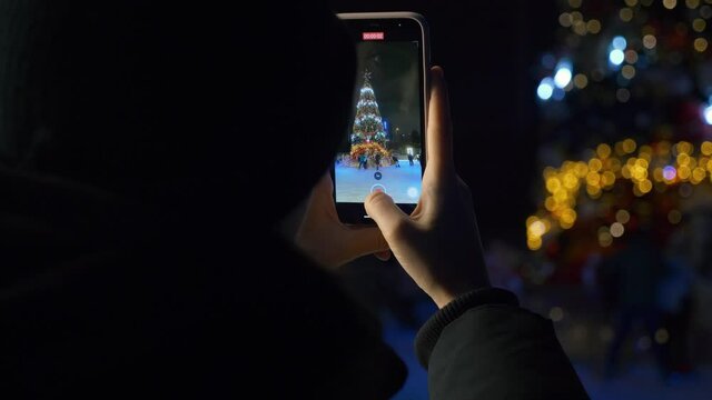 A woman filming near the ice rink during the Christmas holidays
