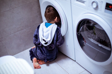 the toddler is looking into the washing machine while wash