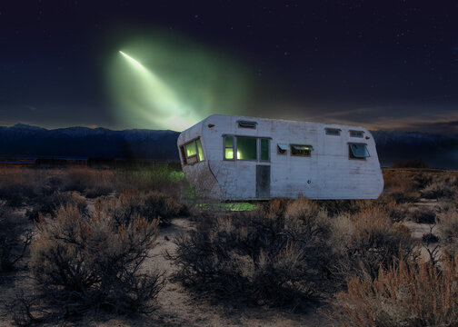 Mysterious light shining on an old abandoned caravan in the desert, USA