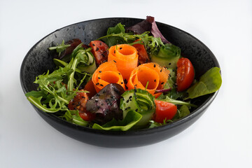 Fresh mixed vegetables salad in a bowl. Raw salad in black bowl on white background