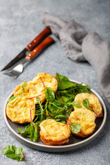 Egg muffins ( bites) and leaves of chard and arugula in a plate on a gray background