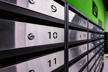 Mailboxes in an apartment building, made of stainless steel, on a green wall