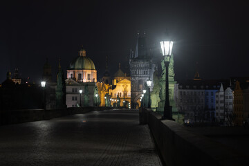 lights on the Charles Bridge on the Vltava river at night and in the background the bridge tower