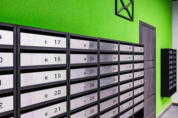 Mailboxes in an apartment building, made of stainless steel, on a green wall