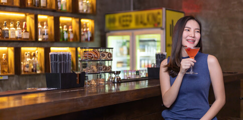 Asian alone women enjoy cocktails in front of a vintage bar, Relaxing activities after work or hangouts, Place of entertainment for young adolescents or night club party.