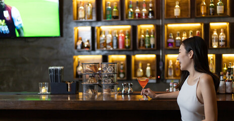 Asian alone women enjoy cocktails in front of a vintage bar, Relaxing activities after work or hangouts, Place of entertainment for young adolescents or night club party.
