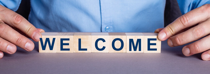 The word WELCOME is made up of wooden cubes by a man. Business concept © Елена Дигилевич