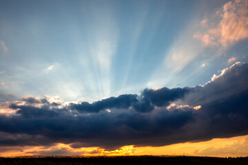 dramatic sky with cloud and sunbeams over a field at sunset