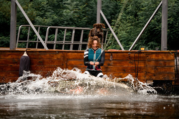 female wakeboarder rides on the water holding rope from motor boat