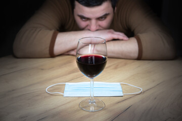 Office worker in cosplay costume of a cow. Guy in the funny animal pyjamas near the a glass of wine. Alcoholic addict, Lost job, unemployment concept, economic crisis. Depression and alcoholism.