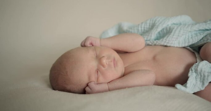 Sleeping newborn baby in plaid. Real time of calm infant child in muslin swaddle lying and sleeping with hands at face
