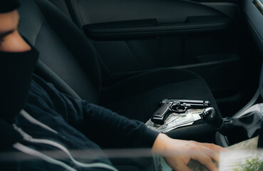 Theft of the car. Man behind the wheel. Gun with money lying on the seat. Carjacking of vehicle. Robbing and crime.