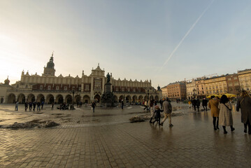 Fototapeta premium Krakow, Poland: Panorama of Cloth Hall (Sukiennice) - located on Main Square (Plac Mariacki) and serving as the handicraft market and people walking in the city center