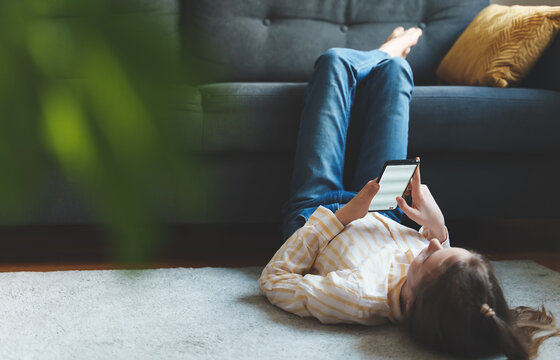 Tween girl with smartphone relaxing at home.