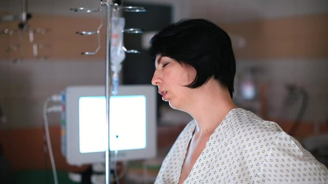 A pregnant woman relaxes in hospital. She holds with her hand, dropper rack. Reducing time interval between contractions.