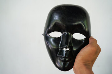 Fototapeta premium Black mask gripped by the right hand. close-up