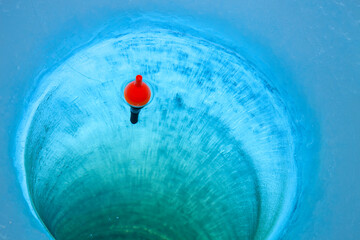 Red bobber in an ice fishing hole © Daniel Thornberg
