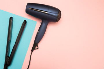 Hair straightener and hairdryer on a colored background. Flat layout with clipboard mockup.