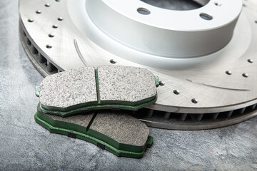 brake pads and perforated brake discs on a stone gray table