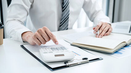 Business man hold pen and press calculator to check investment data