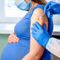 Doctor giving COVID -19 coronavirus vaccine injection to pregnant woman. Vaccination Young Pregnant...