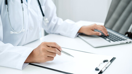 Fototapeta premium Doctor hold pen to record patient data on clipboard and computer